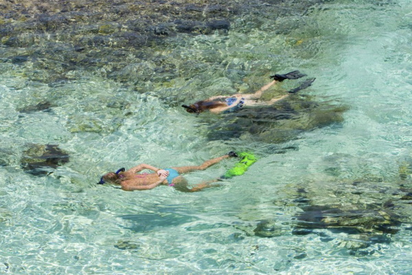 Image of two girls snorkeling in the crystal clear ocean on a girlfriend getaway at Ambergris Cay in Turks and Caicos
